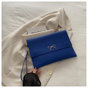 Close-up of blue envelope clutch featuring matte leather and silver bow detail