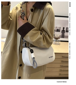 Detail of white barrel bag with wide geometric strap and OOTMAO logo on trench coat