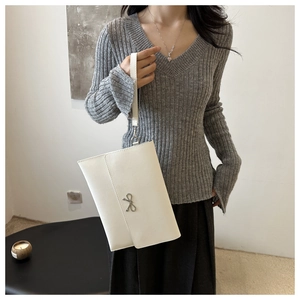 Detail of white envelope clutch bag featuring silver bow fastener and detachable strap