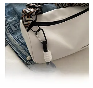 Detail of white casual crossbody bag with ethnic woven strap and smooth black zipper