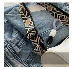 Detail of adjustable geometric ethnic strap on white nylon crossbody pillow bag