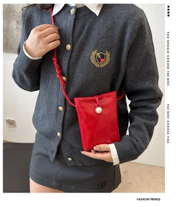 Détail d'un mini sac bandoulière rouge avec bouton perle blanche et bandoulière tressée