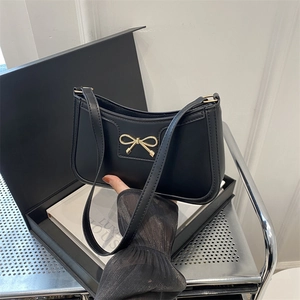 Chic black shoulder bag with gold bow detail and minimalist retro leather design