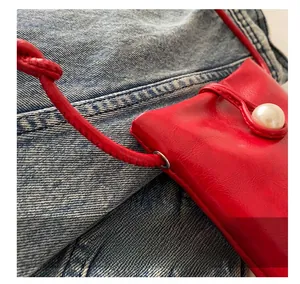 Détail de mini sac rouge en cuir avec fermeture élégante par un bouton perle
