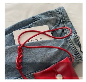 Détail d'un mini sac en cuir rouge avec fermoir perle et bandoulière à nœud tressé