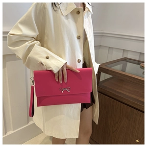 Detail of pink envelope clutch with silver bow metal buckle and wrist strap