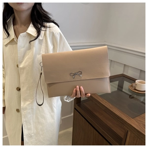 Detail of beige leather envelope clutch bag with silver bow buckle and hand strap
