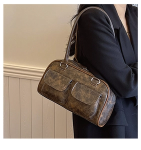 Close-up of vintage brown shoulder bag with decorative front pockets and zip closure