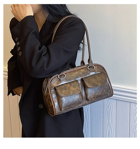 Detail of vintage brown shoulder bag featuring dual front pockets and textured leather