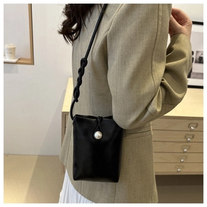Detail of black leather mini phone bag with a large pearl closure and twisted shoulder strap