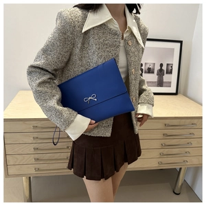 Detail of blue envelope clutch featuring a silver bow accent and matching wristlet strap