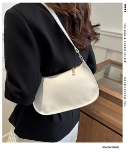 Detail of white glossy patent leather baguette bag with premium gold metal hardware