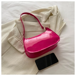 Top view of bright fuchsia patent leather baguette bag with metal buckle on a neutral blazer