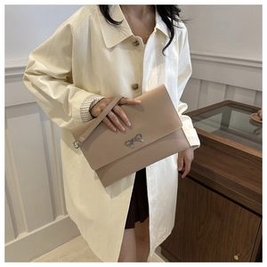 Detail of beige leather envelope clutch bag with silver bow and leather wrist strap