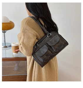 Close-up of black retro leather shoulder bag with dual front pockets and silver hardware