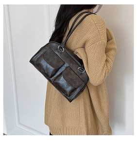 Detail of dark brown vintage shoulder bag featuring twin flap pockets and crackle texture