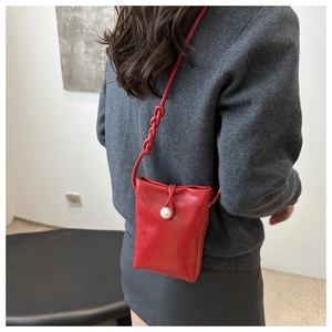 Détail du mini sac à téléphone en cuir rouge avec boucle perle et bandoulière tressée