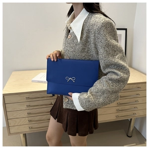 Detail of royal blue envelope clutch featuring a silver metallic bow and textured finish