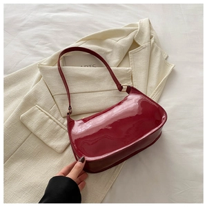 Close-up of deep red patent leather shoulder bag on a light blazer jacket