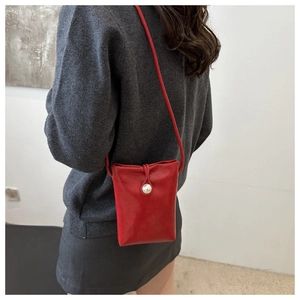 Vue détaillée d'un mini sac de téléphone rouge avec perle et fine bandoulière croisée