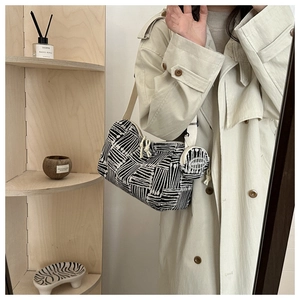Dettaglio della borsa tote in tela a righe con mini portamonete tondo su scaffale moderno
