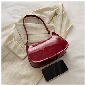 Detail of burgundy patent leather baguette bag shown with smartphone for size reference
