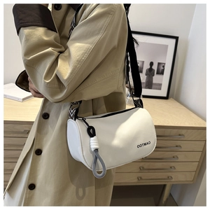 Close-up of white cylindrical crossbody bag with adjustable black strap and rope pendant