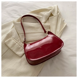Detail of dark red patent leather underarm bag on a chic white blazer background