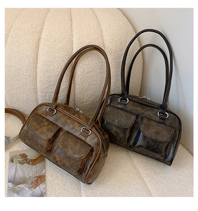 Detail view of retro faux leather shoulder bags with dual front pockets and metal ring handles