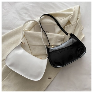 Close-up of minimalist black and white patent leather baguette bags on a beige blazer