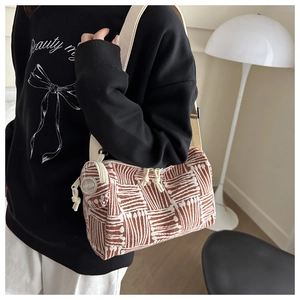 Dettaglio di una borsa a cilindro intrecciata a righe con doppia zip e dettaglio logo
