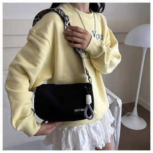 Close-up of black nylon pillow crossbody bag featuring OOTMA logo and geometric wide strap