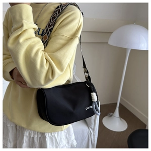 Detail of black nylon crossbody bag featuring a colorful geometric woven wide strap
