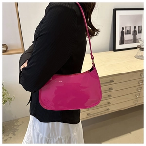 Side view of a vibrant pink patent leather baguette bag worn over the shoulder