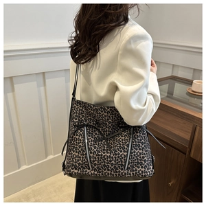 Détail du sac cabas léopard avec des nœuds noirs et des fermetures éclair latérales en métal