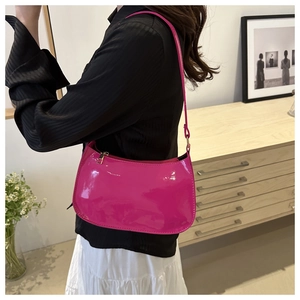 Close-up of bright fuchsia patent leather baguette bag with minimalist zipper design