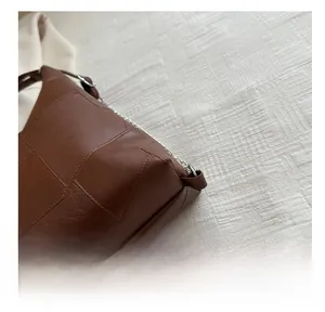 Détail du sac à bandoulière en cuir marron avec patchwork carré et chaîne argentée