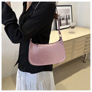 Pink hobo bag with glossy finish styled on shoulder with striped shirt and white skirt