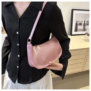 Detail of pink mirror patent leather hobo bag with gold zipper worn by a model