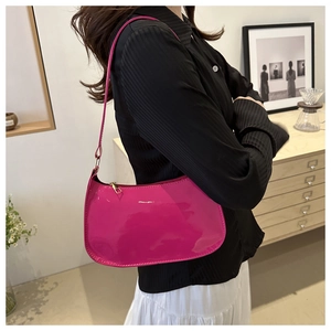 Detailed view of magenta glossy patent leather shoulder bag with gold zipper and strap