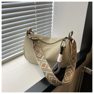 Close-up of canvas dumpling bag with geometric woven strap and rope pendant