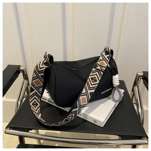 Detail of waterproof nylon dumpling bag with geometric woven strap on a leather chair