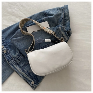 Detail of white half-moon bag with ethnic style woven geometric shoulder strap