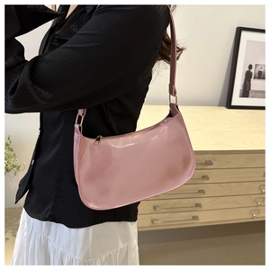 Close-up of pink patent leather shoulder bag worn by model in a stylish interior