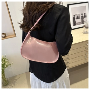 Detail of pink half-moon shoulder bag in glossy leather with golden buckle on model