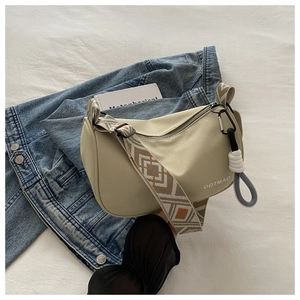 Detail of beige oxford crossbody bag with ethnic woven strap and decorative cord pulls