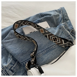 Close-up of geometric woven shoulder strap on white canvas bag with adjustment buckle
