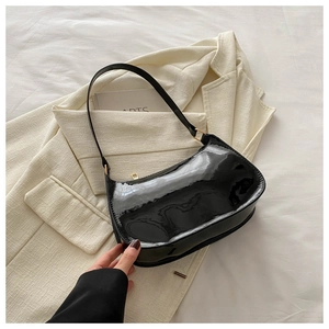 Detailed macro of black patent leather baguette bag with shiny gold zipper and hardware