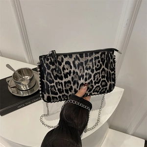 Leopard print crossbody bag with silver studs and chain strap shown in hand