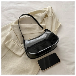 Detail of glossy black patent leather baguette bag with shiny gold buckle and mirror finish